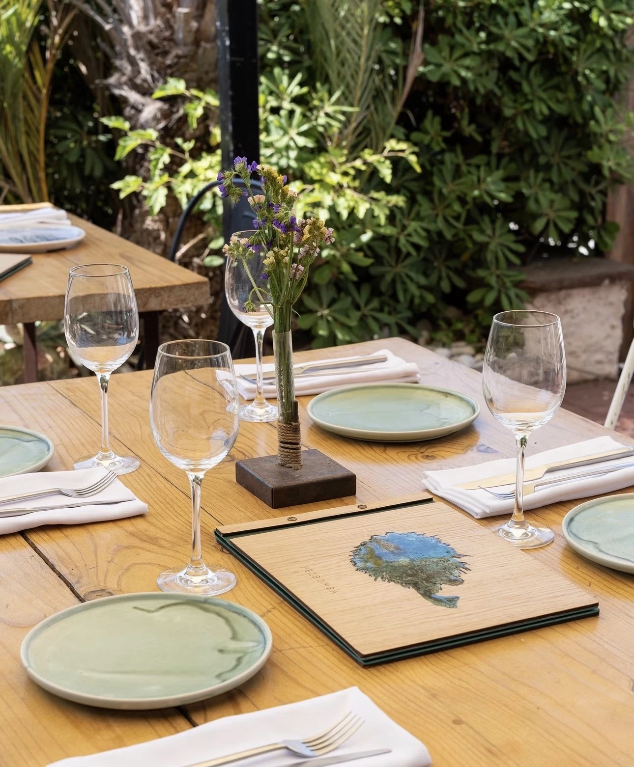 Mesa puesta en la terraza con la carta y platos de cerámica